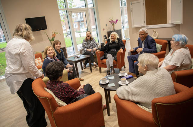 ten people sat on chairs chatting and laughing