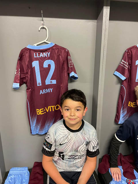 a young football player sat by a football shirt