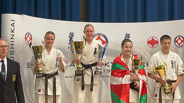 four karate fighters holding trophies