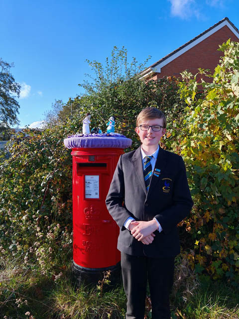 a boy stood by a postbox