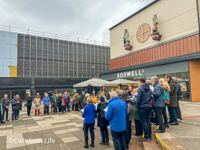 group of people watch a choir in a town square