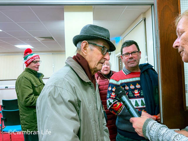 a 105 year-old man in trilby hat chats to a woman