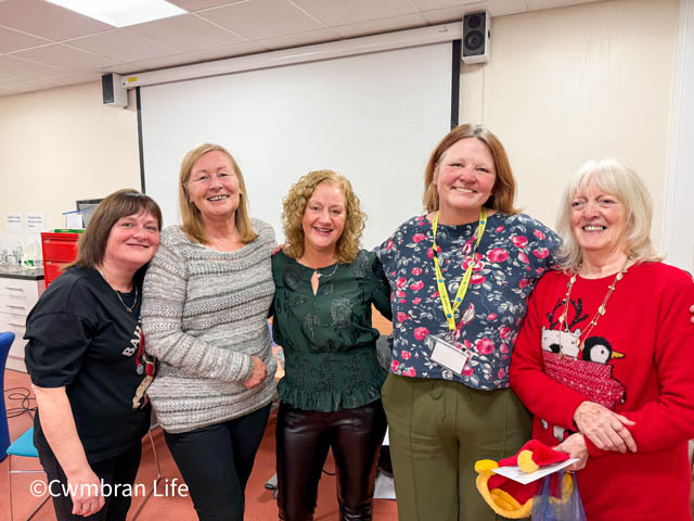 five women in row smiling at camera