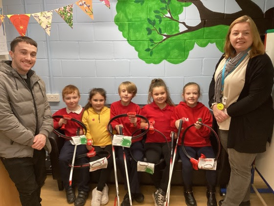 pupils and staff hold litter picking kit