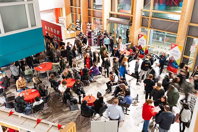 dozens of young people in a large room at a college open day