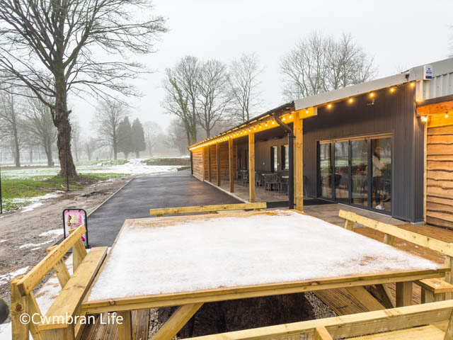 a snow covered table by a log cabin building