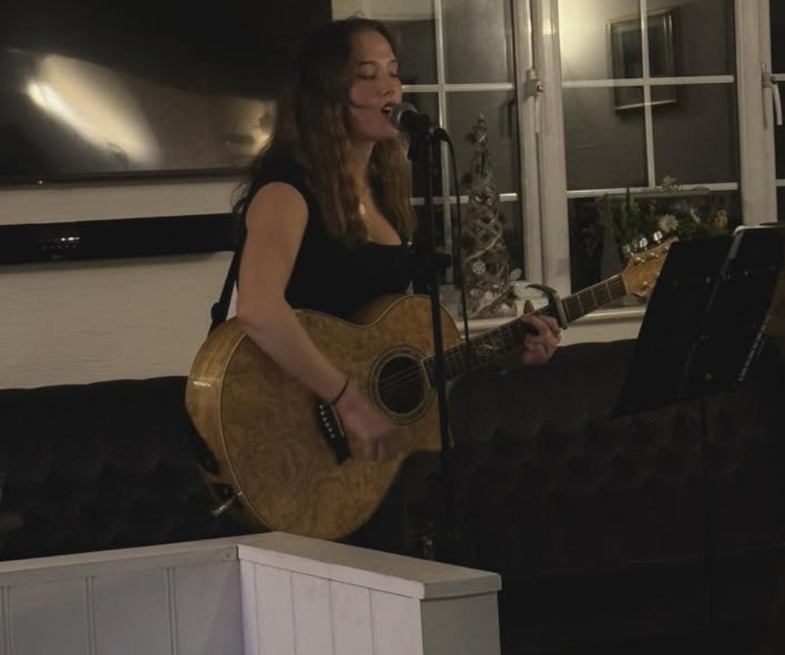 Chloe Griffin singing and playing her guitar in a pub