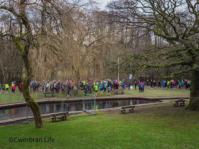 runners at the start of a race by some trees and a pond