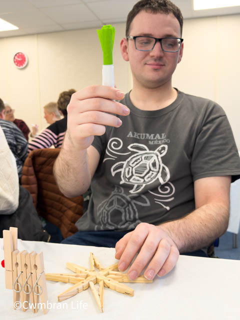 a man holds up leek he's made in an arts and craft class