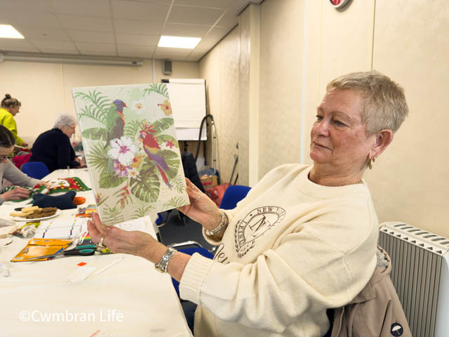 a woman holds up a piece of art