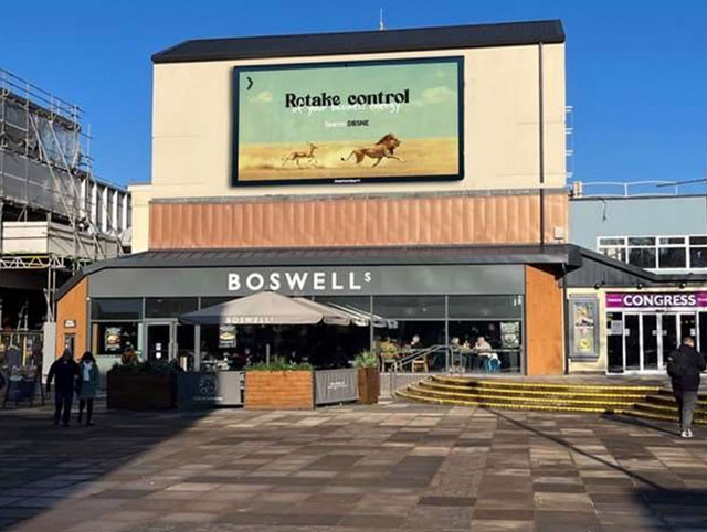 a large cafe with a large TV screen on the wall above it