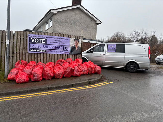 a pile of red rubbish bags by a van