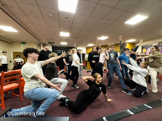 a group of young actors with their hands in their air