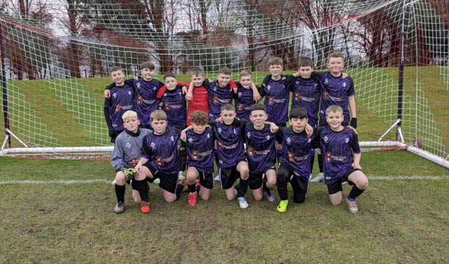 A boys football team have a photo in front of the goals