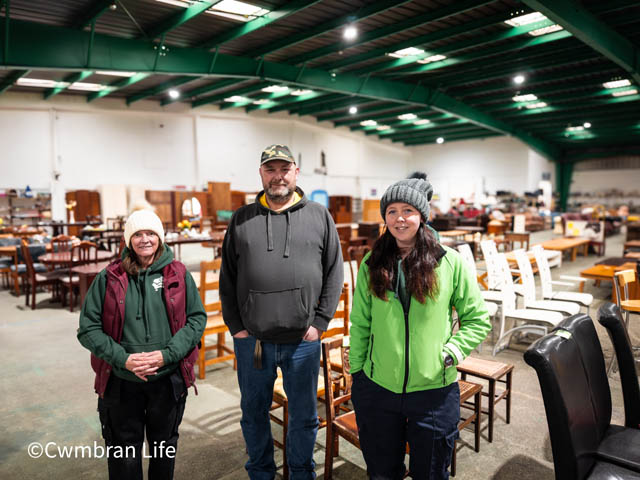 two women and a man stood in a warehouse