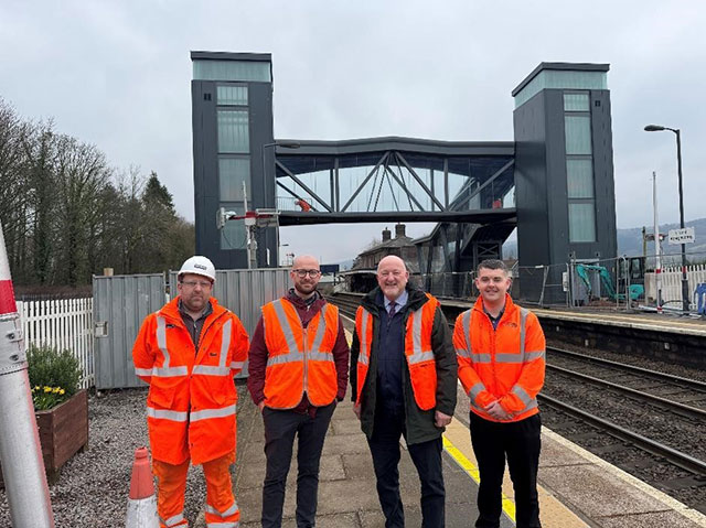 From left: Daniel France, project manager Centregreat, Rhys Jehu station manager Transport for Wales, Peter Fox, MS for Monmouth and Tomos Roberts of Network Rail with the new accessible bridge at Abergavenny railway station behind them.