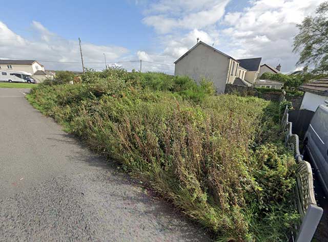 a lane next to a field with a house in the distance