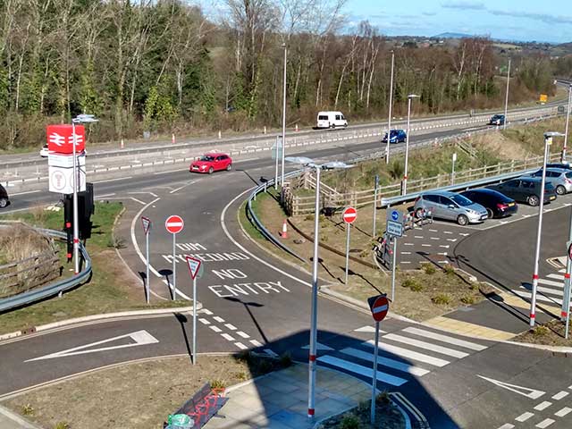 an entrance off a busy road into a car park