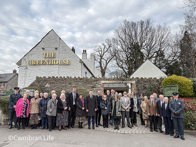 a large group of people outside a pub called The greenhouse