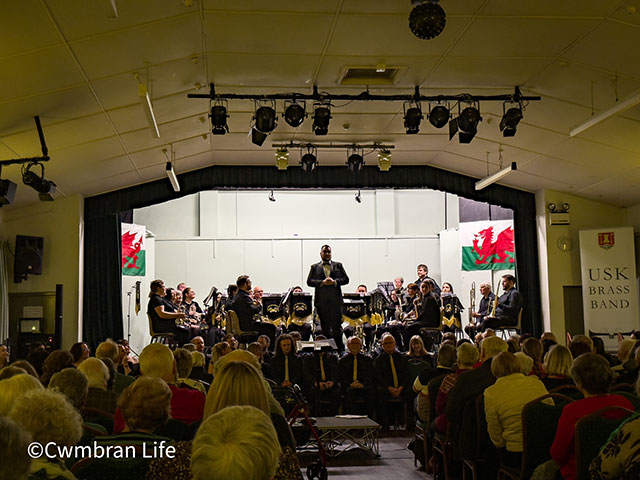 man on stage with brass band behind him