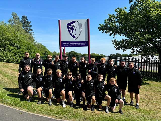 a boys football team outside their school for a team photo