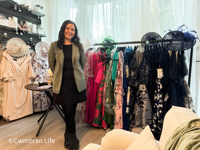a woman in a shop stood by a rail of dresses