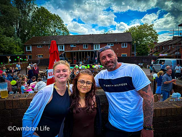 a teenager between her parents outside a music gig in a pub car park