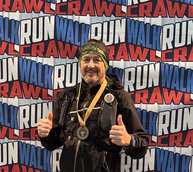 a man wearing a medal in front of a wall with the words run wall