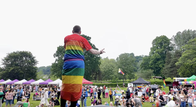 a man in a pride flag on stage in front of a crowd