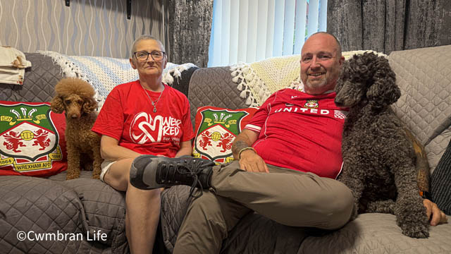 a man and woman on a sofa in red tops sat next to two dogs