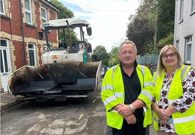 a man and woman stood by a road being dug up