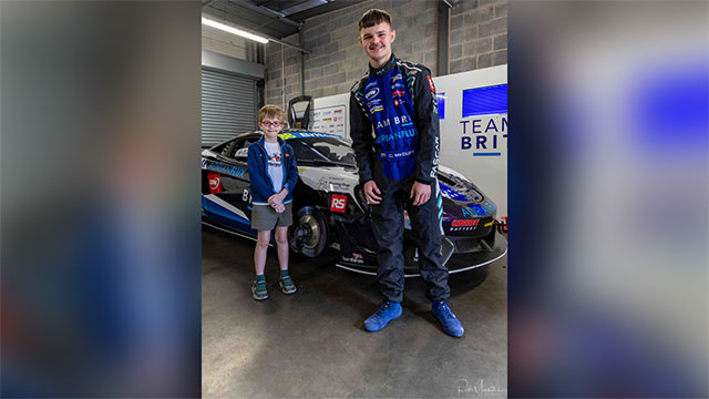 a young boy and a teenage boy by a racing car