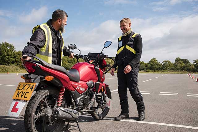 two men stood by a motorbike