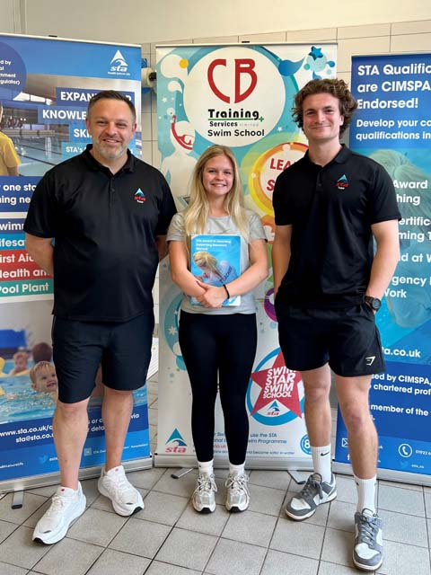 Two men and a woman stood by a board advertising the CB training services swim school