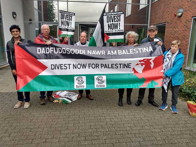 a group of people hold a 'divest now for palestine'