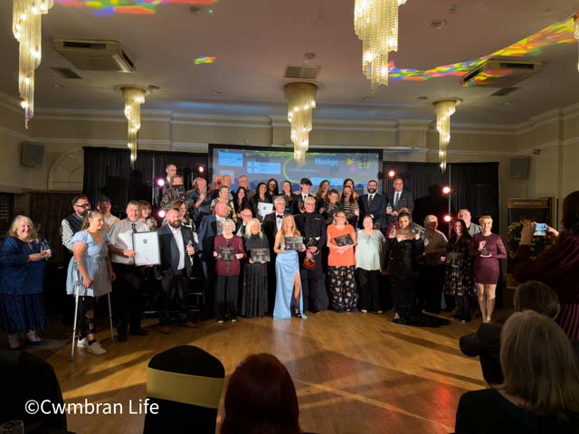 a group of people stood on a dancefloor holding awards