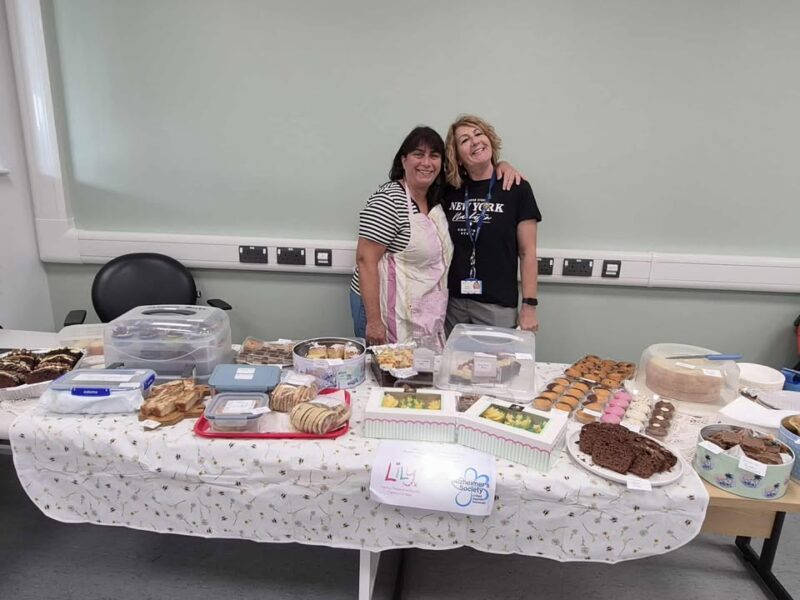 two women stood by a table full of cakes