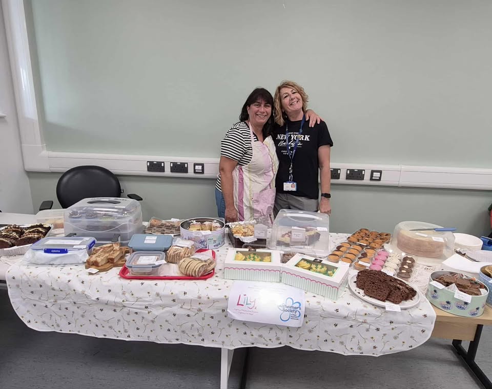 two women stood by a table full of cakes