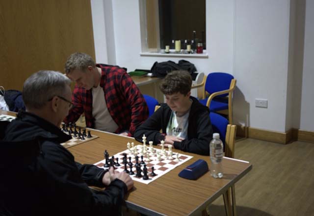 a man and young boy play cheses