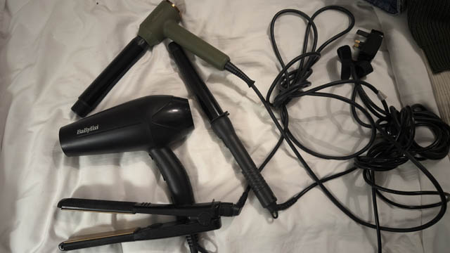 hairdryers and hair straighteners on a bed