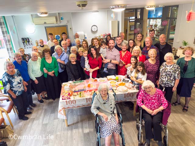 family and friends stand around Myfanwy Thomas- who has just turned 100