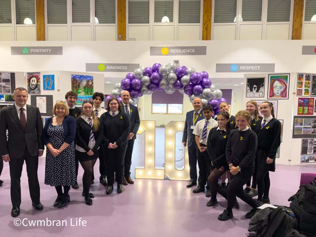 a group of pupils, teachers and politicians stood by a balloon arch