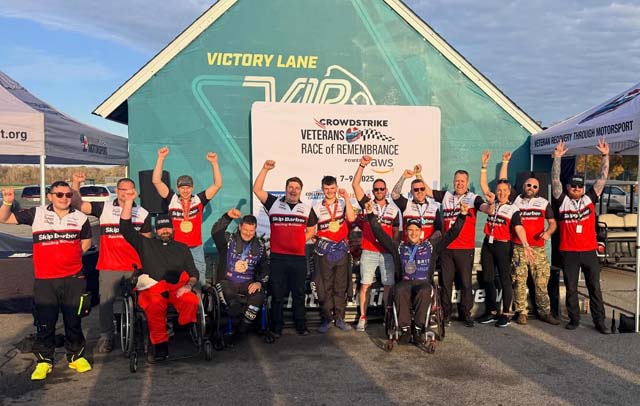 a group of racing drivers and staff standing by a car