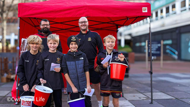 junior rugby players stand with two of their coaches