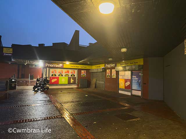 a premier shop in the evening with lights on outside it