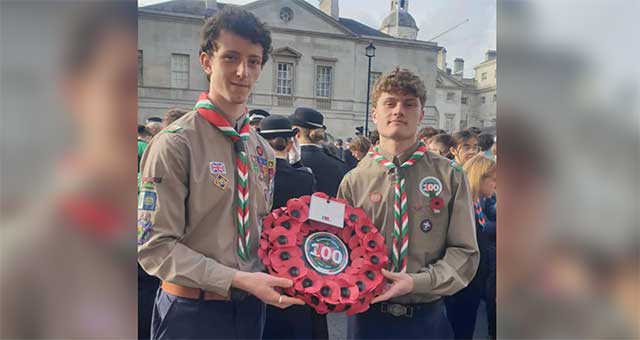 two teenage boy scouts hold a poppy wreate