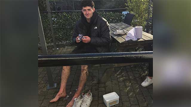 a man sat on a bench cleaning his muddy legs