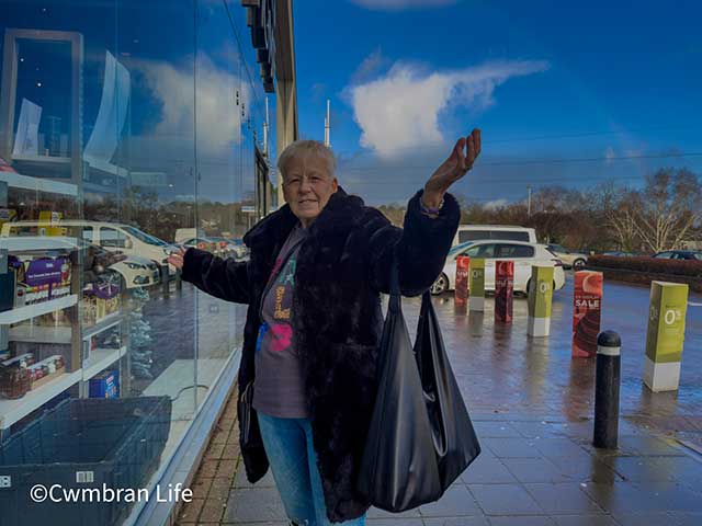a woman stood outside a shop on a sunny day
