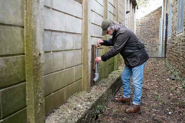 a man by an outside tap and pipe