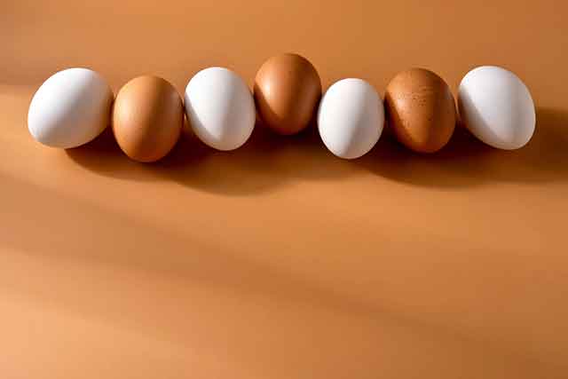 Brown and white chicken egges on beige background.